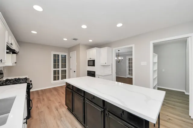 a large kitchen with kitchen island a stove a sink a refrigerator and wooden floor