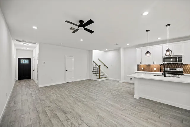 a large white kitchen with wooden floors and white walls