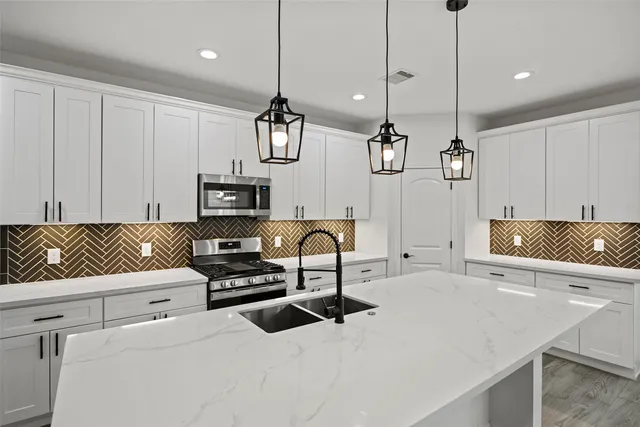 a large kitchen with stainless steel appliances kitchen island granite countertop a sink a stove and a refrigerator