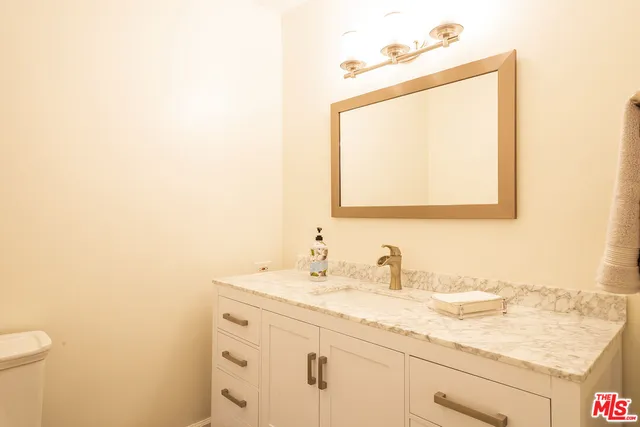 a bathroom with a granite countertop sink a toilet and a mirror