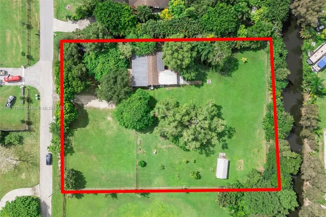 a view of a white house with a big yard and potted plants