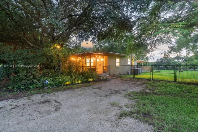 a view of a backyard with plants and large trees