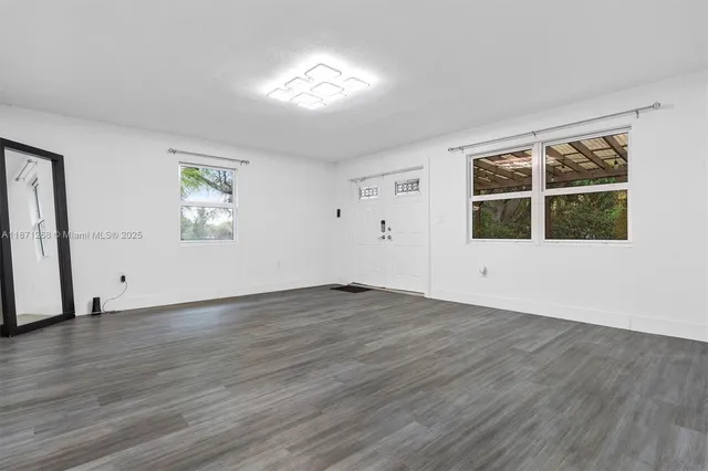 a view of an empty room with wooden floor and windows