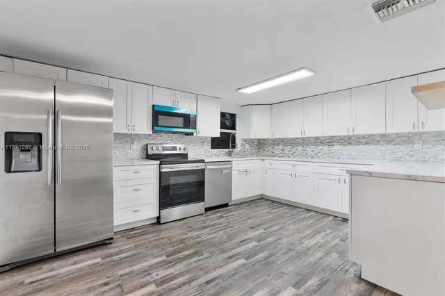 a kitchen with granite countertop cabinets stainless steel appliances and wooden floor