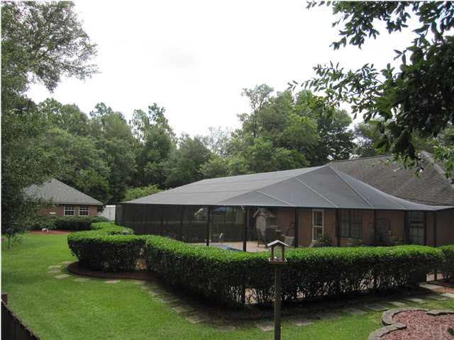 5918 Country Club Road Milton, FL 32570 - Photo 5 of 25 View of guest house in background just beyond the screened in pool. Nothing but wooded area behind you. 2 walk gates & 1 double drive gate on property.
