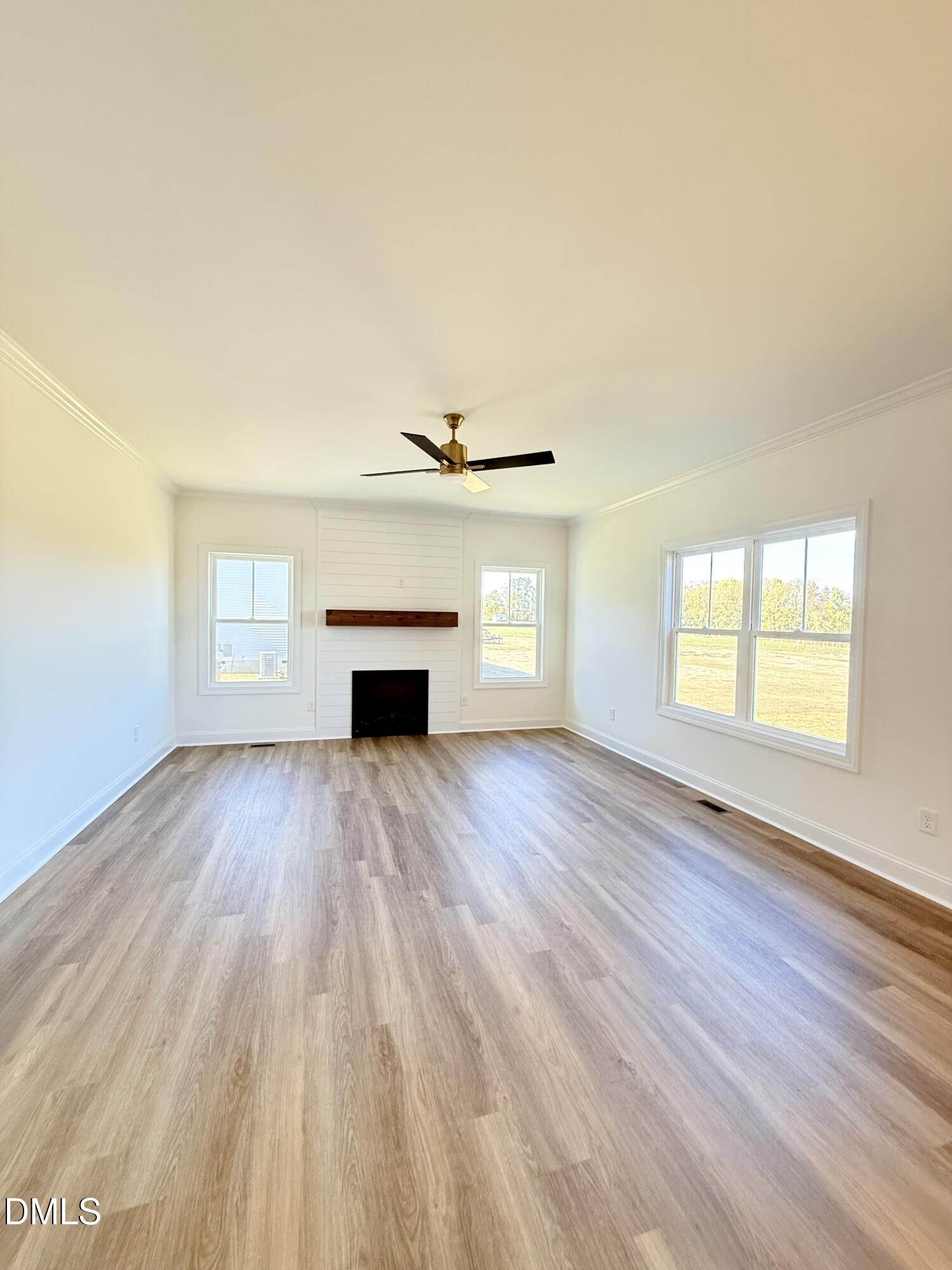 6800 Fire Tower Road Spring Hope, NC 27882 - Photo 14 of 36 an empty room with wooden floor a fireplace and windows