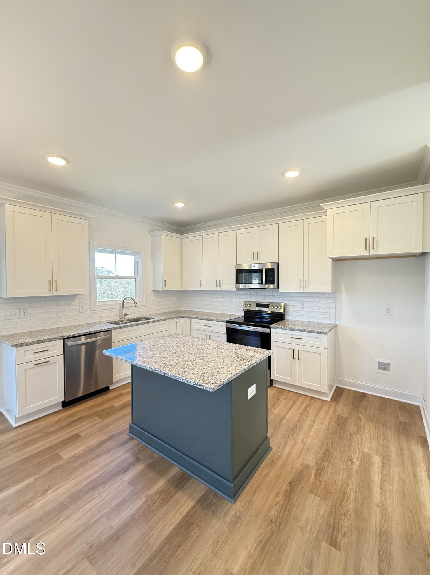 6800 Fire Tower Road Spring Hope, NC 27882 - Photo 7 of 36 a large kitchen with stainless steel appliances granite countertop a stove a sink dishwasher and a refrigerator with wooden floor