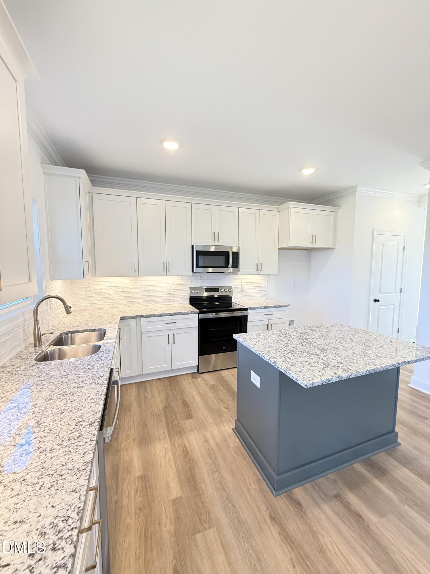 6800 Fire Tower Road Spring Hope, NC 27882 - Photo 8 of 36 a large kitchen with granite countertop a stove top oven a sink dishwasher and white cabinets with wooden floor