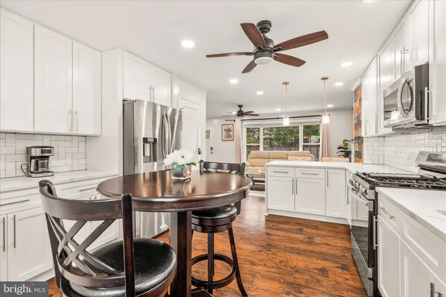 a kitchen with stainless steel appliances kitchen island granite countertop a dining table and chairs