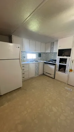 a kitchen with a refrigerator and white cabinets