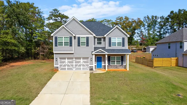 a front view of house with yard and trees in the background