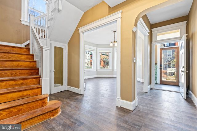 a view of an empty room with wooden floor fireplace and a window