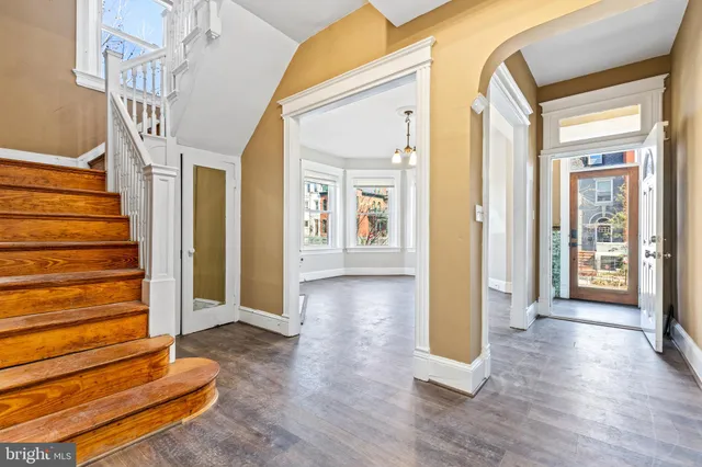 a view of an empty room with wooden floor fireplace and a window