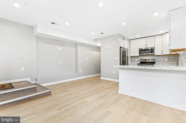 a kitchen with kitchen island granite countertop a sink cabinets and stainless steel appliances