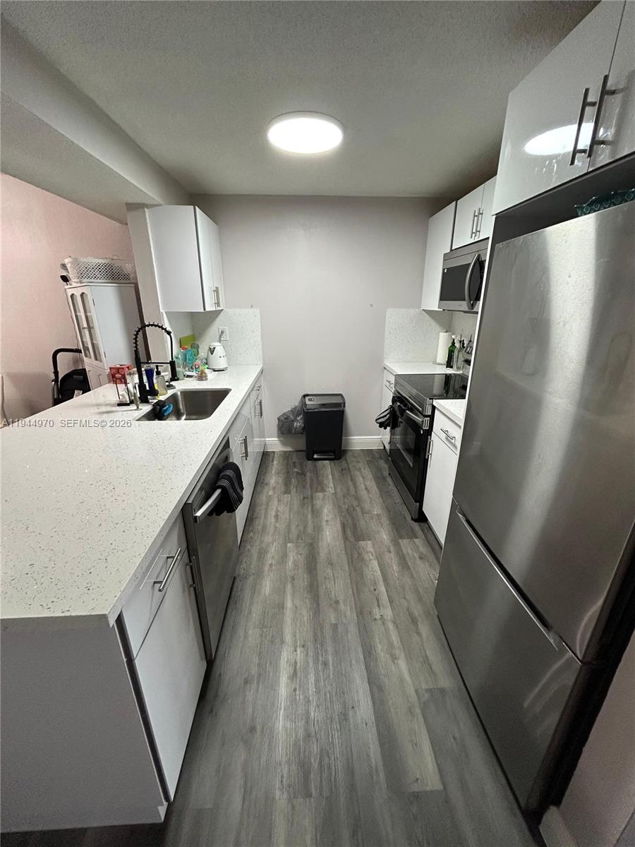 7402 Northwest 75th Street Tamarac, FL 33321 - Photo 24 of 38 a kitchen with sink a refrigerator and wooden floor