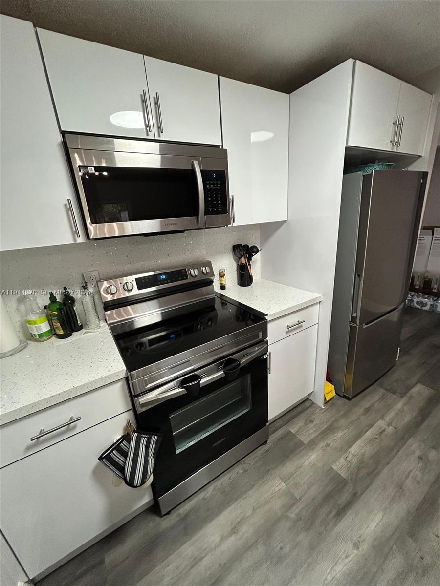 7402 Northwest 75th Street Tamarac, FL 33321 - Photo 25 of 38 a kitchen with stainless steel appliances a stove a microwave and a refrigerator