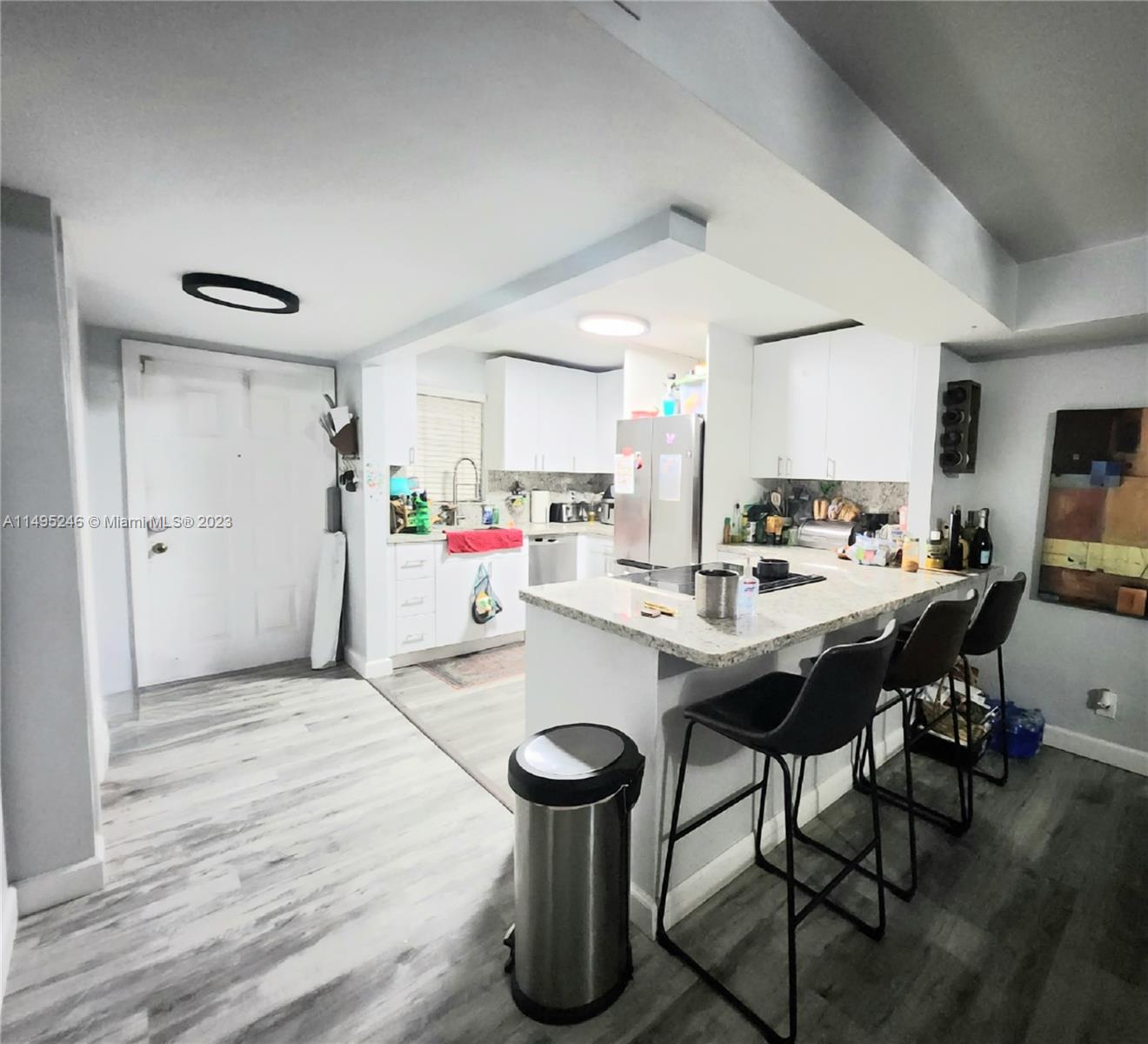 a kitchen with stainless steel appliances kitchen island granite countertop a table chairs and a refrigerator