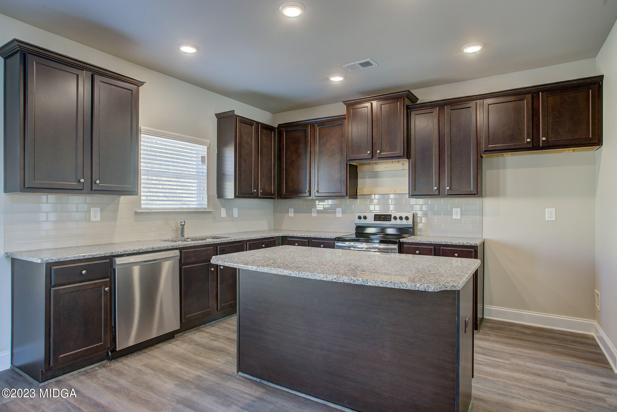 155 Cherokee Rose Drive Jackson, GA 30233 - Photo 10 of 32 a kitchen with kitchen island granite countertop wooden cabinets stainless steel appliances and a window