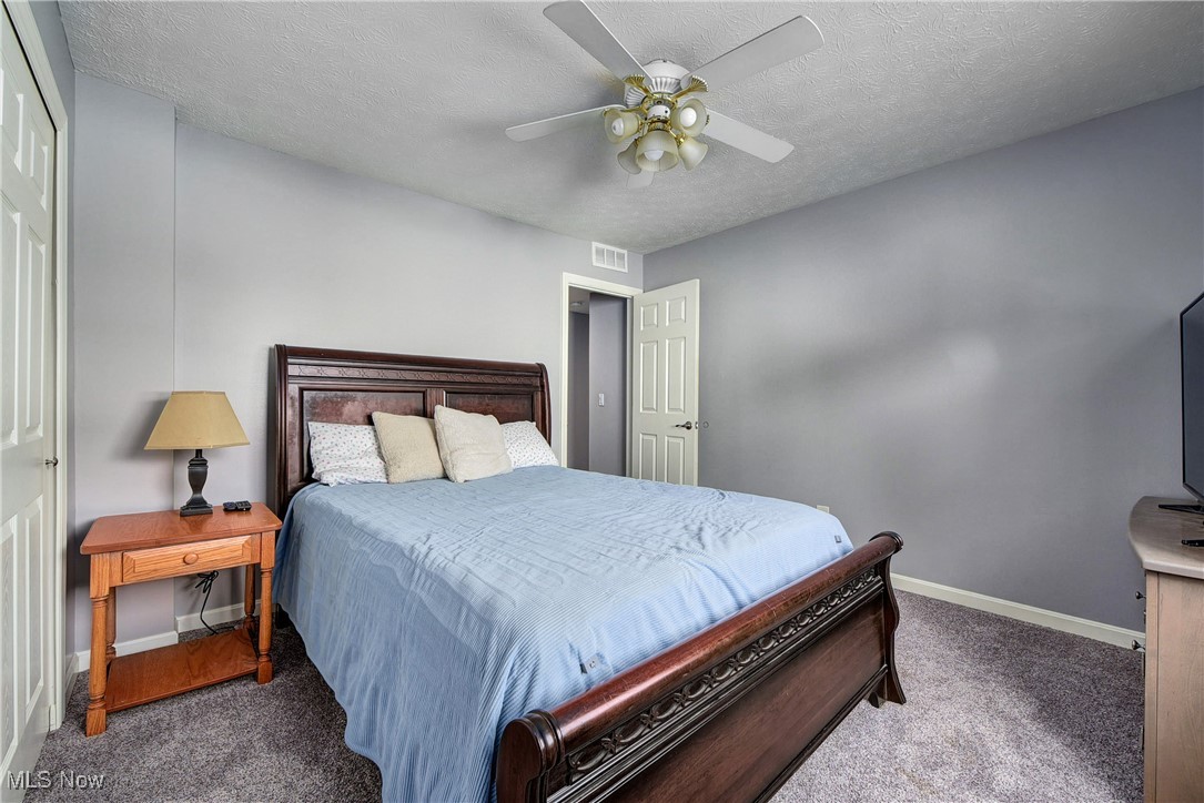 49 North Carpenter Road Brunswick, OH 44212 - Photo 22 of 39 Bedroom featuring a textured ceiling, dark carpet, ceiling fan, and a closet