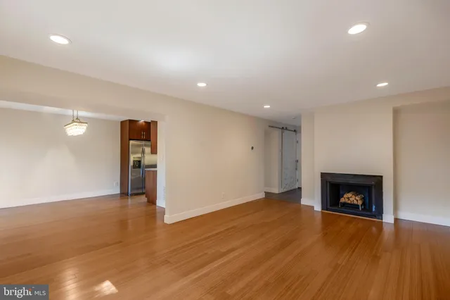 a view of an empty room with wooden floor and a fireplace