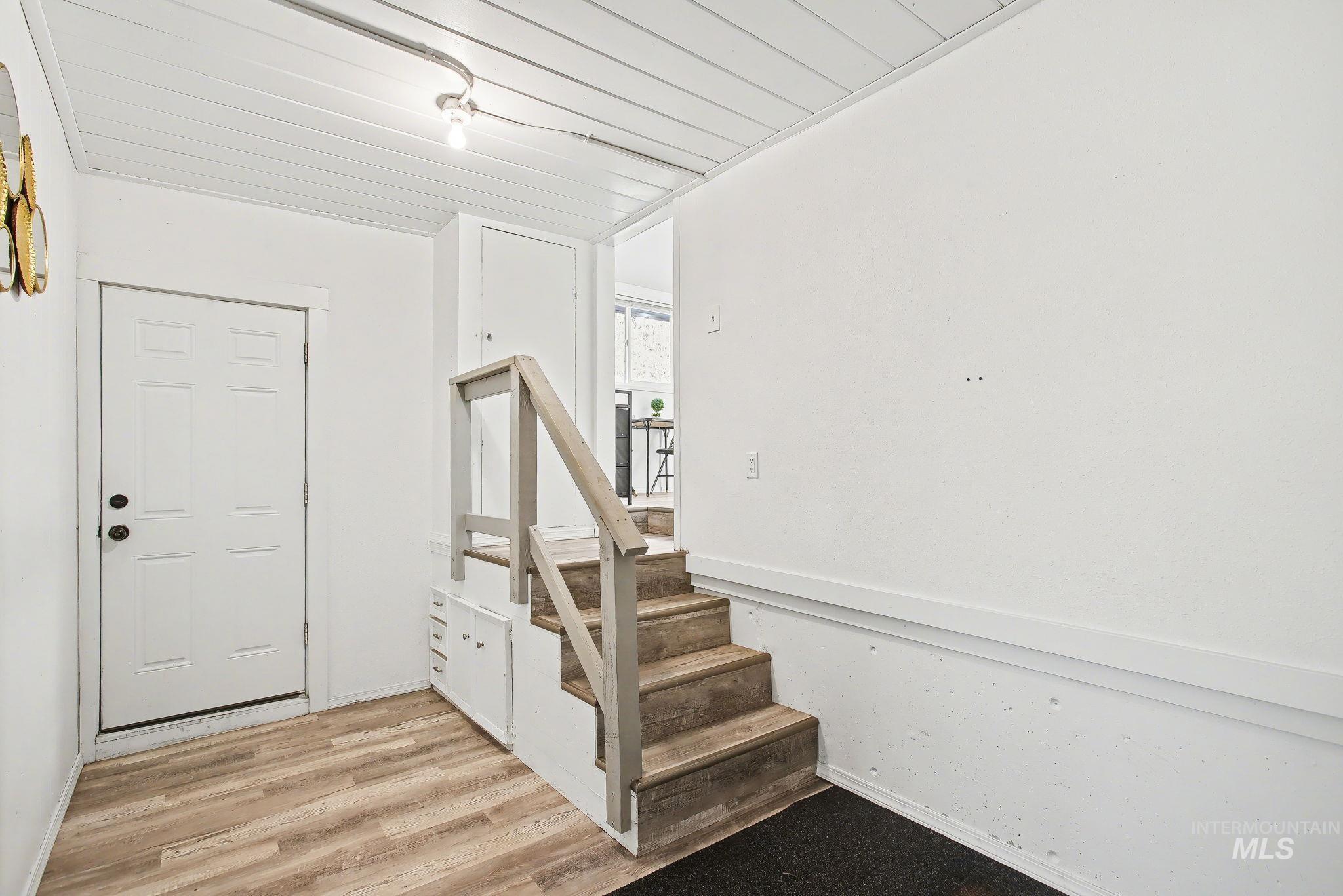 150 Elm Street Orofino, ID 83544 - Photo 20 of 36 Entryway featuring wood-finish flooring, a white paneled door, and a staircase with a wood railing