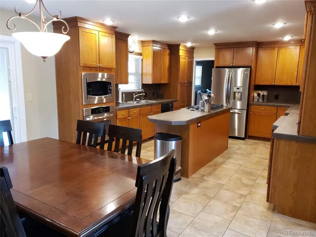 a kitchen with stainless steel appliances granite countertop a table chairs sink refrigerator and microwave