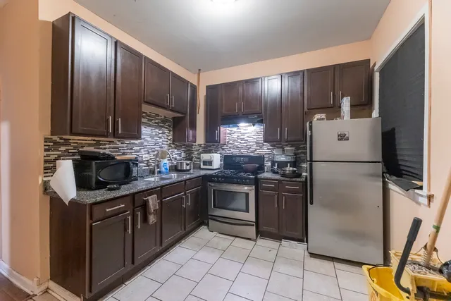 a kitchen with stainless steel appliances granite countertop a refrigerator and a stove top oven