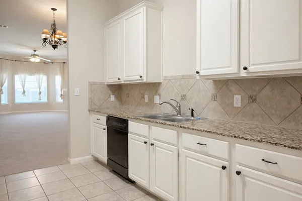 a kitchen with granite countertop white cabinets and stainless steel appliances