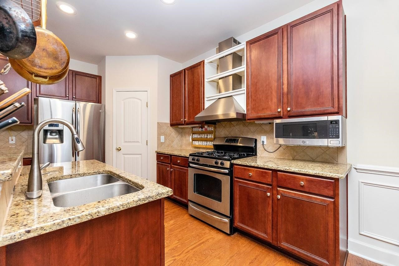 2033 Weston Green Loop Cary, NC 27513 - Photo 5 of 24 a kitchen with stainless steel appliances granite countertop a sink stove and cabinets