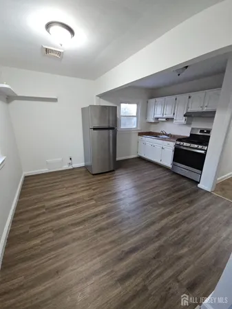 a view of kitchen and empty room with wooden floor