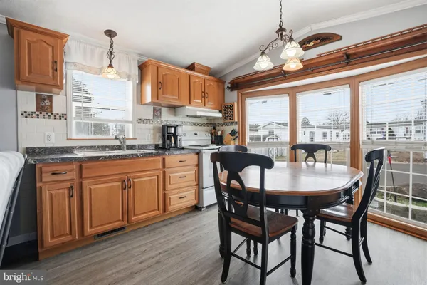 a open kitchen with stainless steel appliances granite countertop a stove a refrigerator a sink dishwasher a dining table and chairs with wooden floor