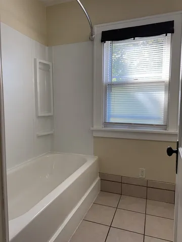 a bathroom with a bathtub and next to a window
