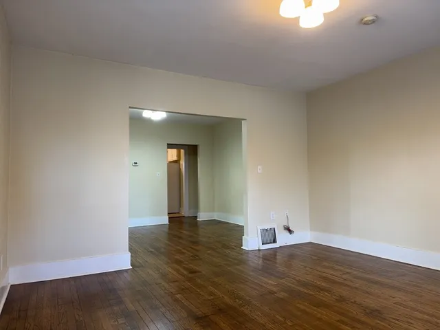 a view of an empty room and wooden floor and a window