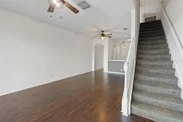 an empty room with windows and chandelier fan