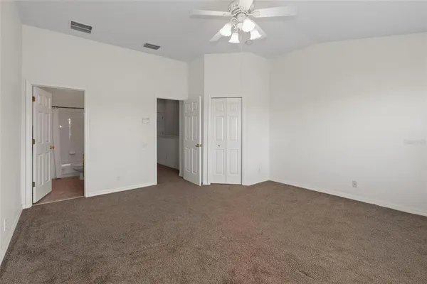 an empty room with a chandelier fan and windows