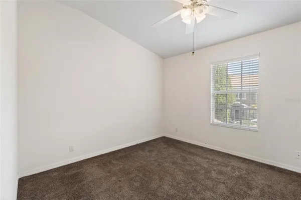 an empty room with a chandelier fan and windows