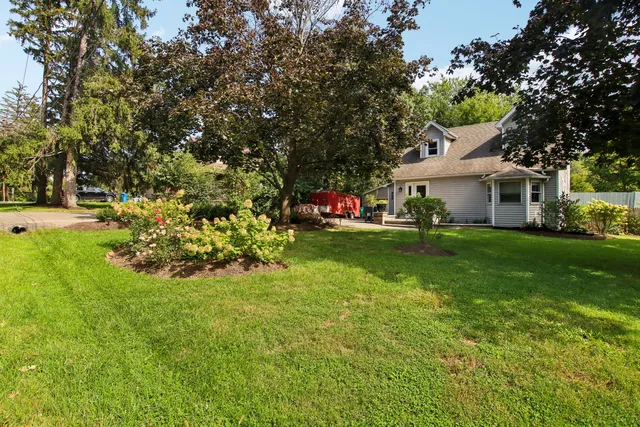 a front view of a house with a garden and trees