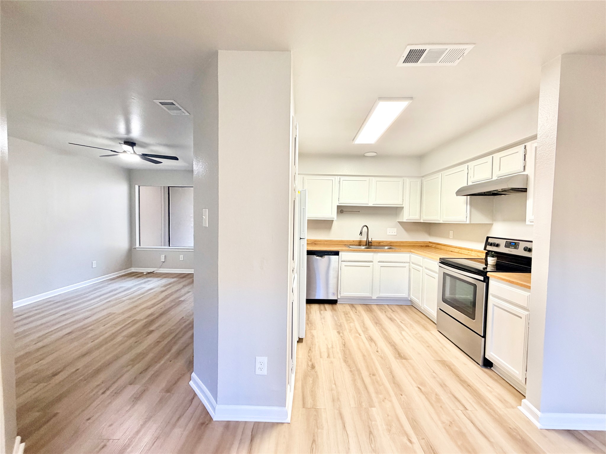1730 Timber Ridge Road, Unit 152 Austin, TX 78741 - Photo 13 of 26 Kitchen with stainless steel appliances, white cabinetry, under cabinet range hood, and light wood finished floors