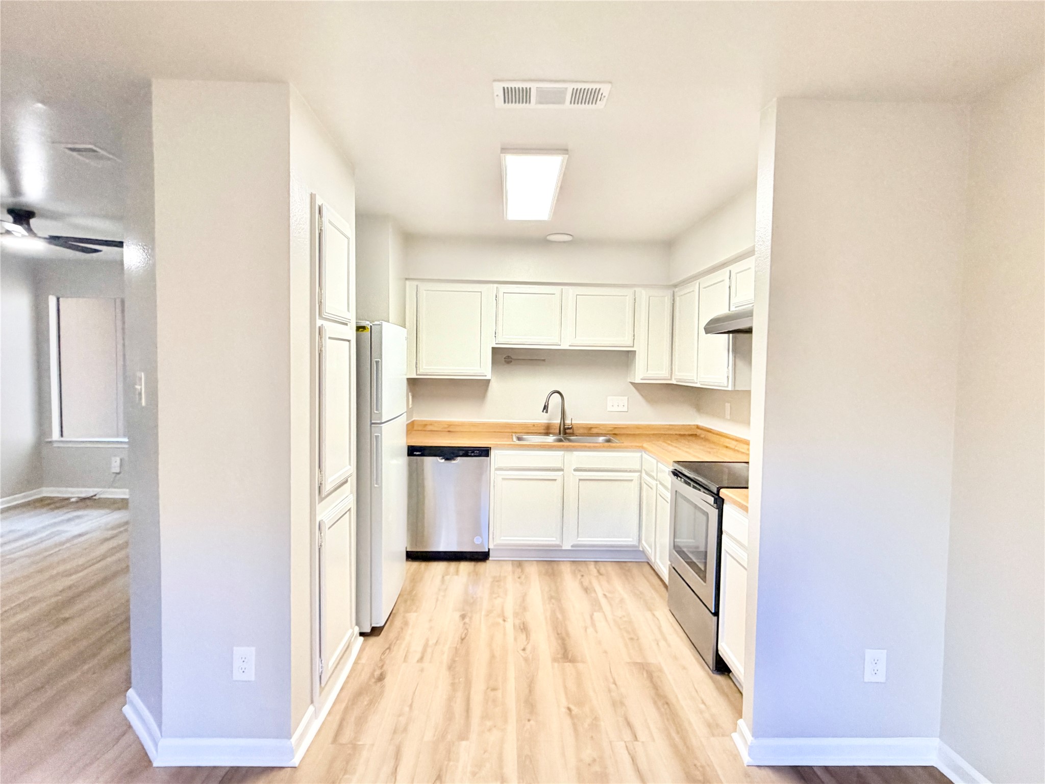 1730 Timber Ridge Road, Unit 152 Austin, TX 78741 - Photo 14 of 26 Kitchen featuring white cabinets, appliances with stainless steel finishes, light wood-style flooring, under cabinet range hood, and butcher block countertops