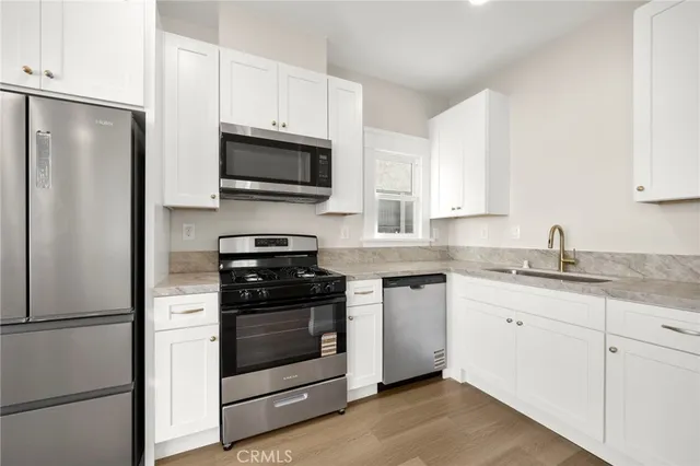 a large kitchen with a refrigerator a sink dishwasher a stove and oven with wooden floor