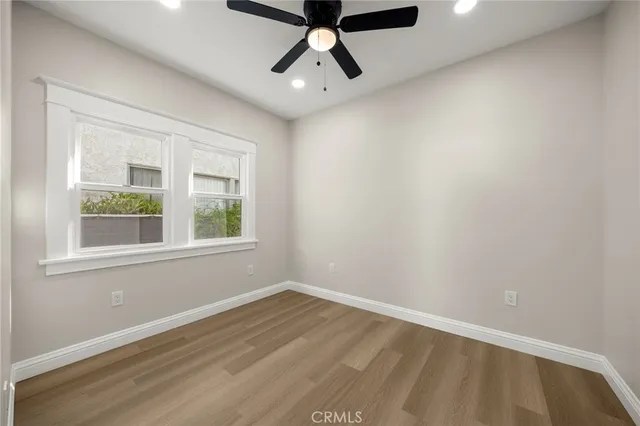 an empty room with wooden floor and ceiling fan