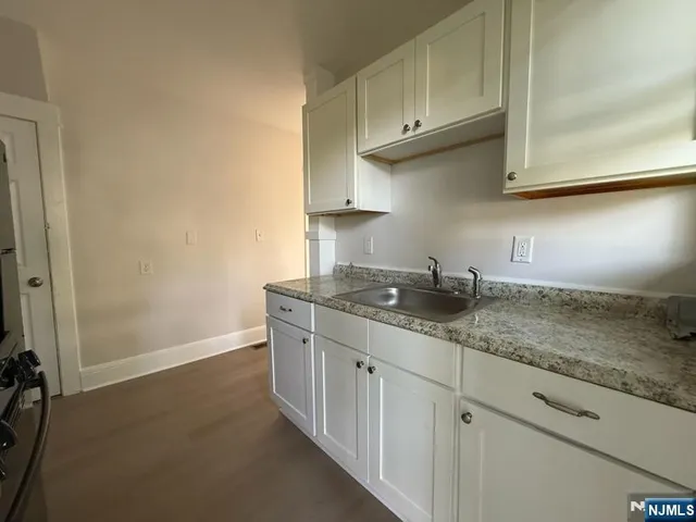 a kitchen with granite countertop white cabinets and a sink