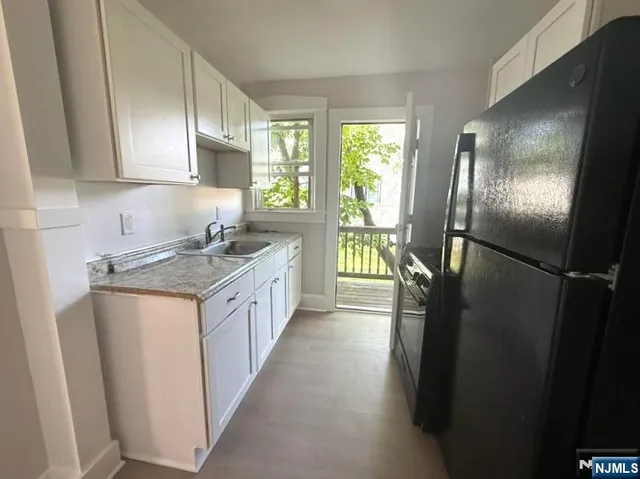 a kitchen with stainless steel appliances granite countertop a refrigerator a sink a stove and a refrigerator