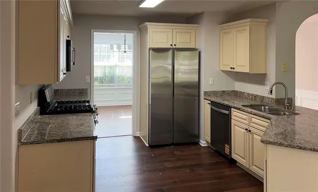 a kitchen with granite countertop a refrigerator stove and sink