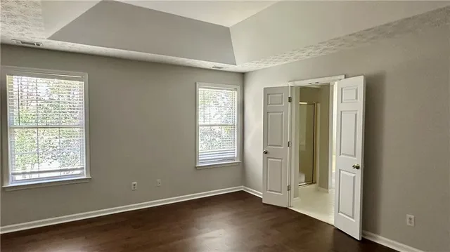an empty room with wooden floor and windows