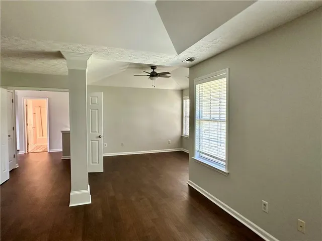 an empty room with wooden floor and windows