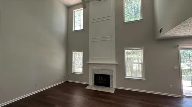 an empty room with wooden floor a fireplace and windows