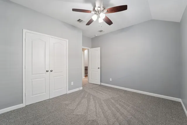 an empty room with closet and a chandelier fan
