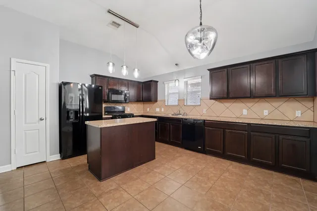 a kitchen with stainless steel appliances granite countertop a refrigerator a sink dishwasher a stove with wooden cabinets