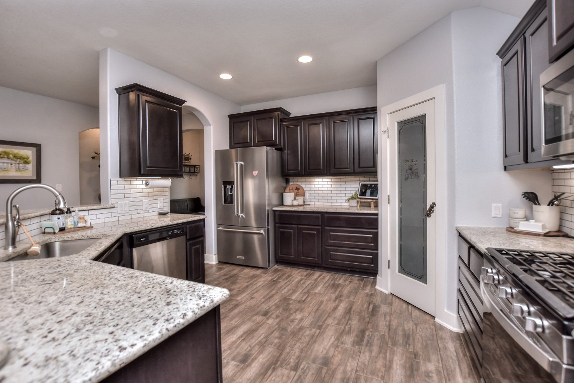 a kitchen with stainless steel appliances kitchen island granite countertop a refrigerator stove and oven